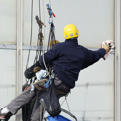 Homme en dehors sur des sangles nettoyant des vitres d'un batiment